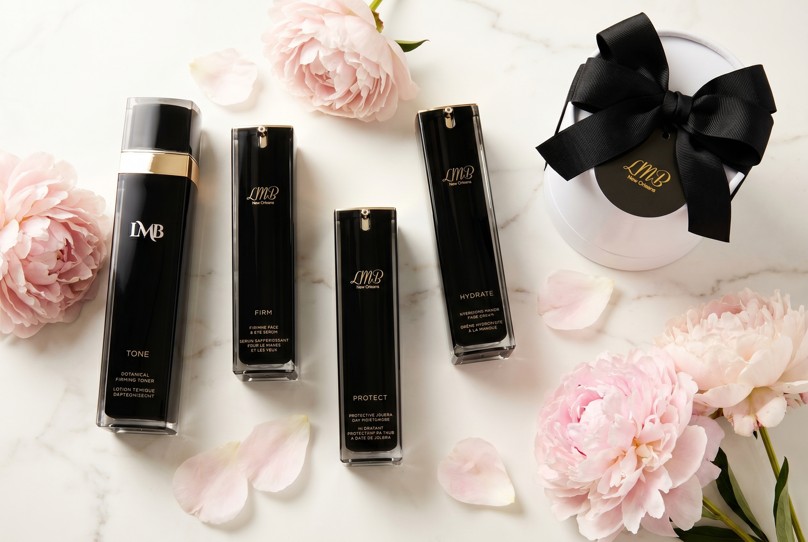 LMB beauty products arranged on a bright vanity with flowers, candles, and brushes.